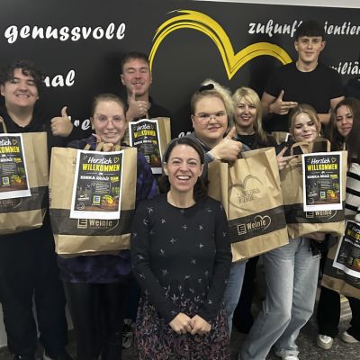 Die neuen Azubis 2026 von EDEKA Weinle mit Frau Weinle-Günter, lächelnd mit Willkommenstüten und erhobenen Daumen
