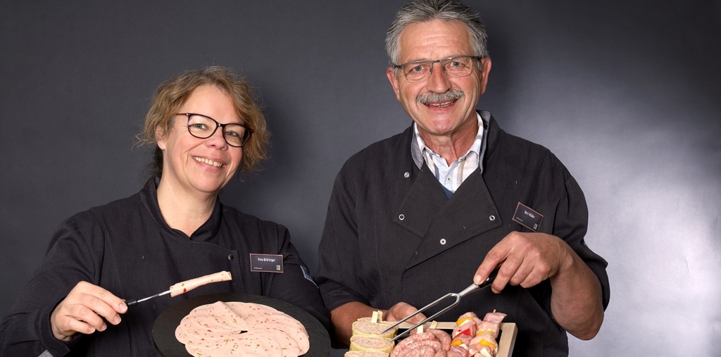 Eine Mitarbeiterin und ein Mitarbeiter mit Fleischgabeln und Wurstplatten