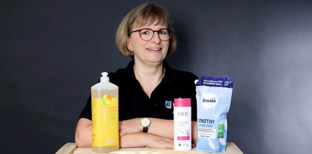 Mitarbeiterin im Edeka T-Shirt mit Drogerieartikel im Vordergrund