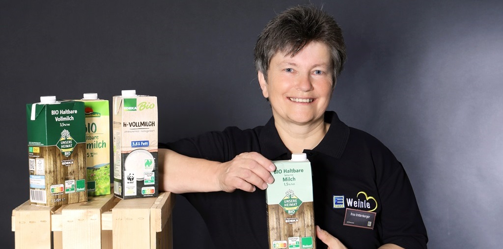 Mitarbeiterin im Edeka T-Shirt mit Milchtüten im Vordergrund